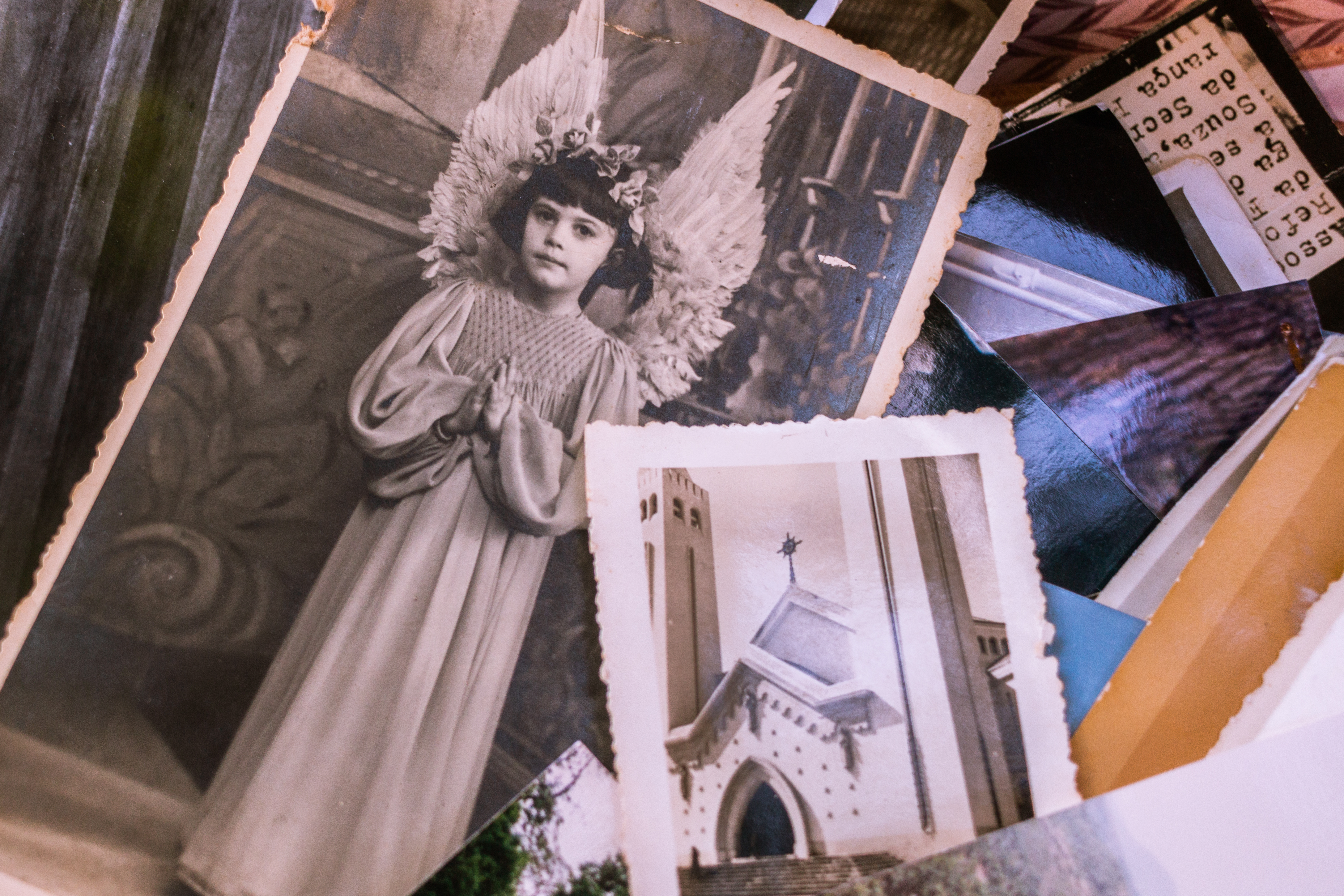 Free Close-up Of Old Black and White Photos Of A Young Girl In An Angel Costume And A Church Stock Photo